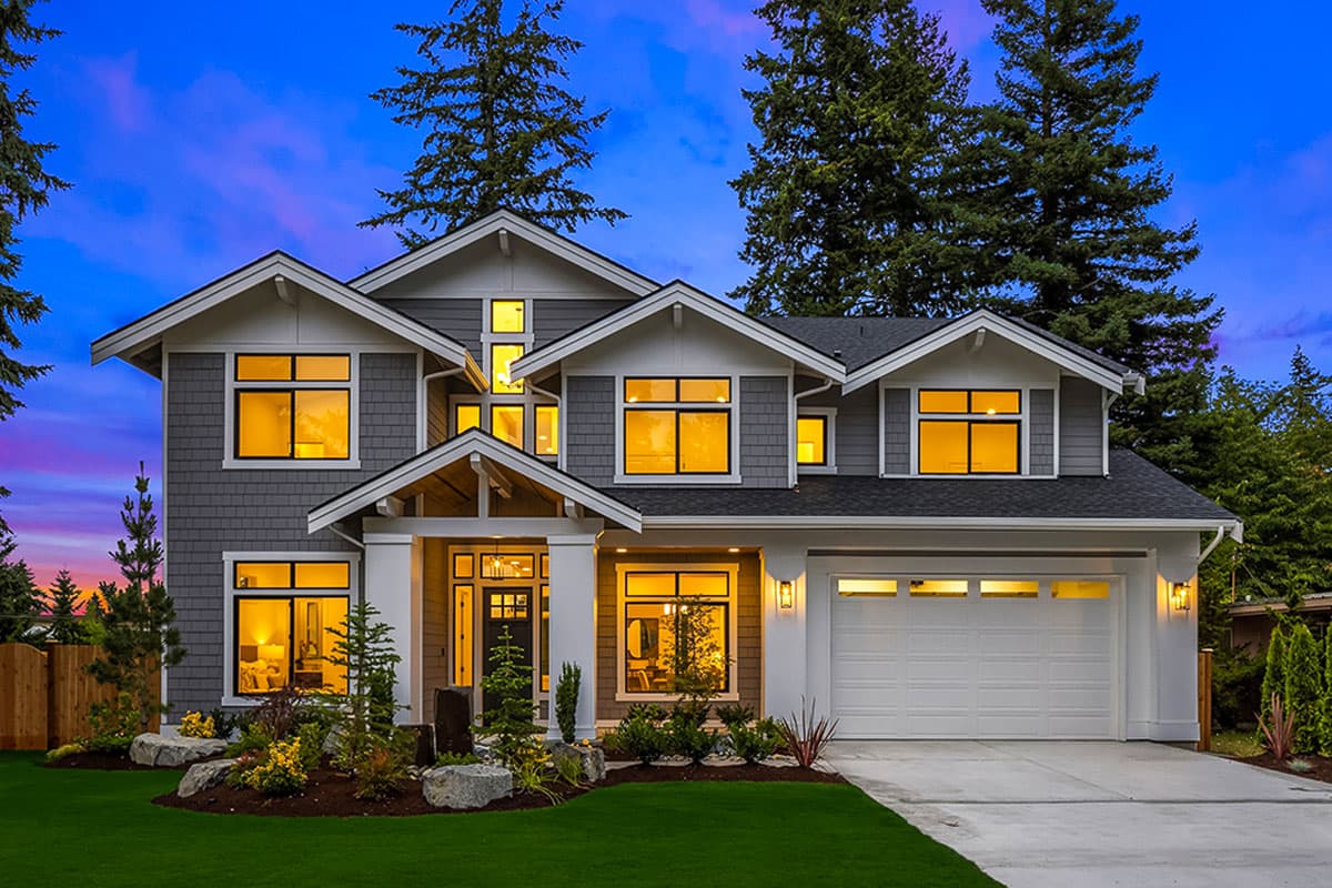 House plan exterior. Two-story Craftsman home with gabled roof, front porch, and attached two-car garage. Features multiple dormers and shake siding.