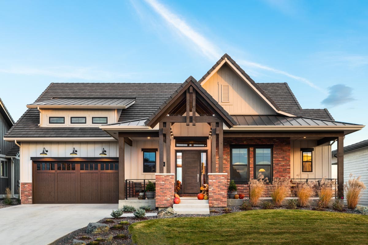 House plan exterior with Craftsman style, featuring a gabled entry, dormers, and a prominent garage. The home is one story.