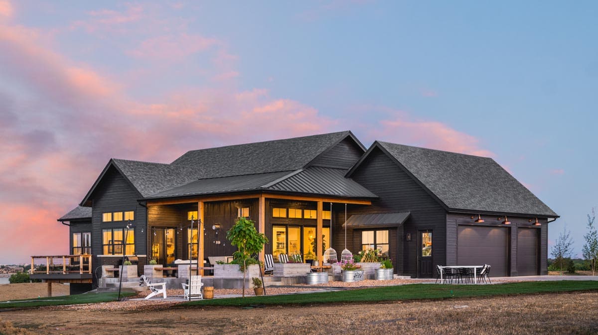 Modern Farmhouse exterior with dark siding, covered porch, multiple gables, and a three-car garage.