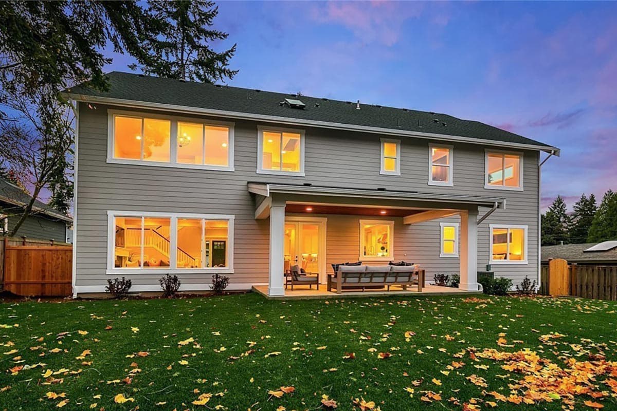 Two-story house plan exterior with covered patio, multiple windows, and lap siding. 