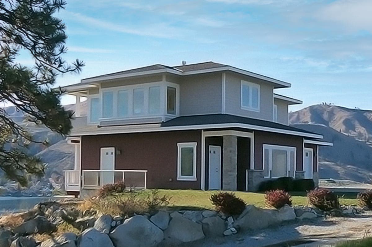 House plan exterior: Two-story modern home with a hip roof, upper-level bay windows, and a main level with stone accents and multiple entries.