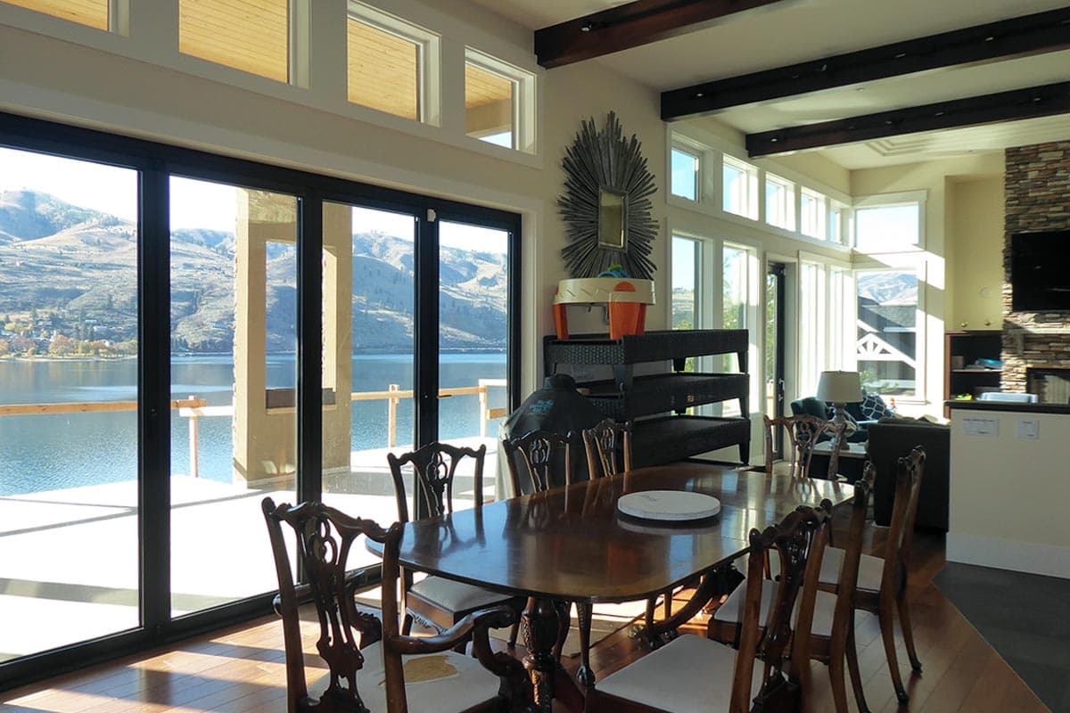 Dining area with large sliding glass doors, wood beams, and lake view.