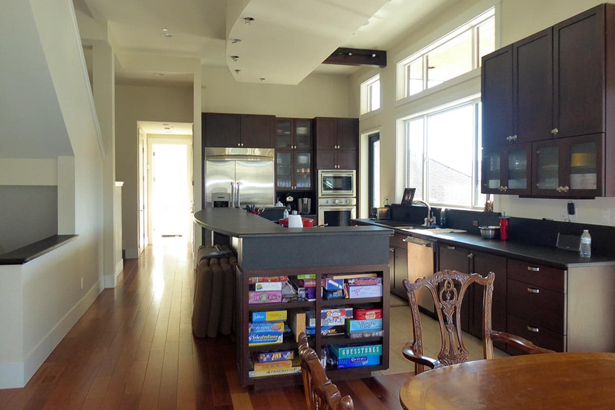 Open concept kitchen with dark wood cabinets, curved island with game storage, and large windows.