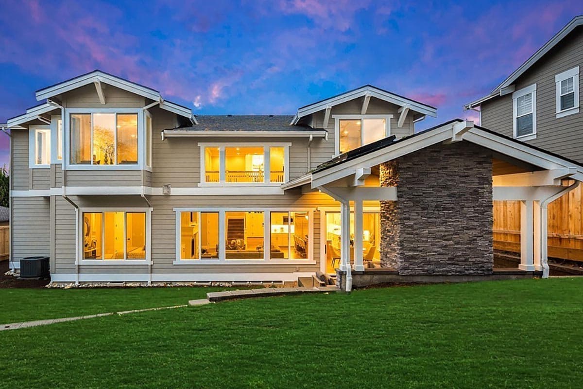 House plan exterior: Two-story home with multiple gables, a stone-clad chimney, and a covered patio.