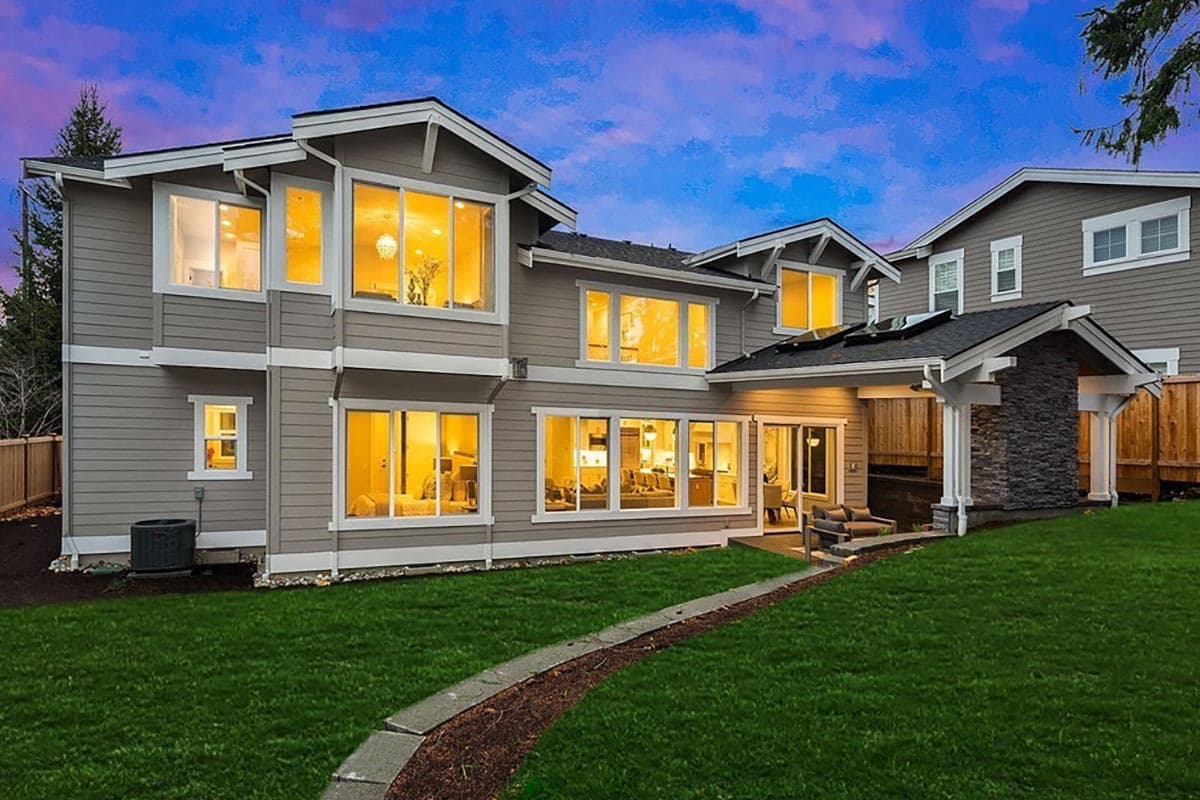 House plan exterior view of a two-story home with large windows, gables, and a covered patio with stone accent.