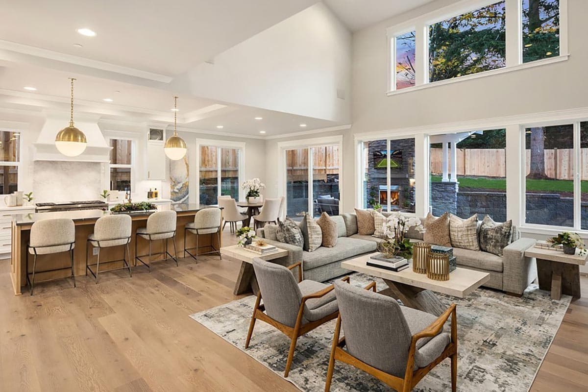 Open concept living and dining area with a large kitchen island, sectional sofa, and a stone fireplace.