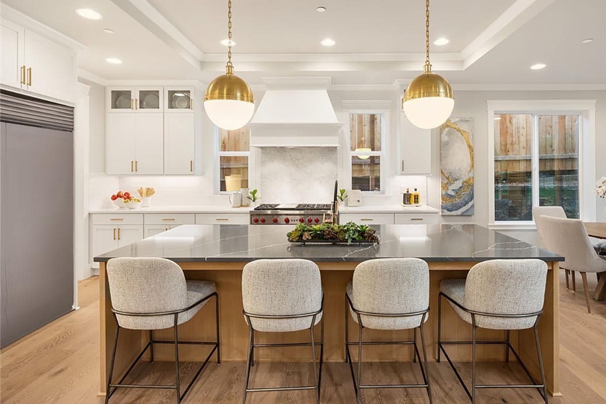 Kitchen featuring a large island with seating, white cabinetry, stainless steel appliances, and pendant lighting.