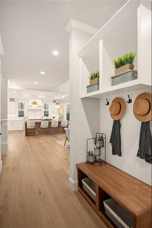 Interior hallway with built-in storage bench and view of kitchen with island and pendant lights.
