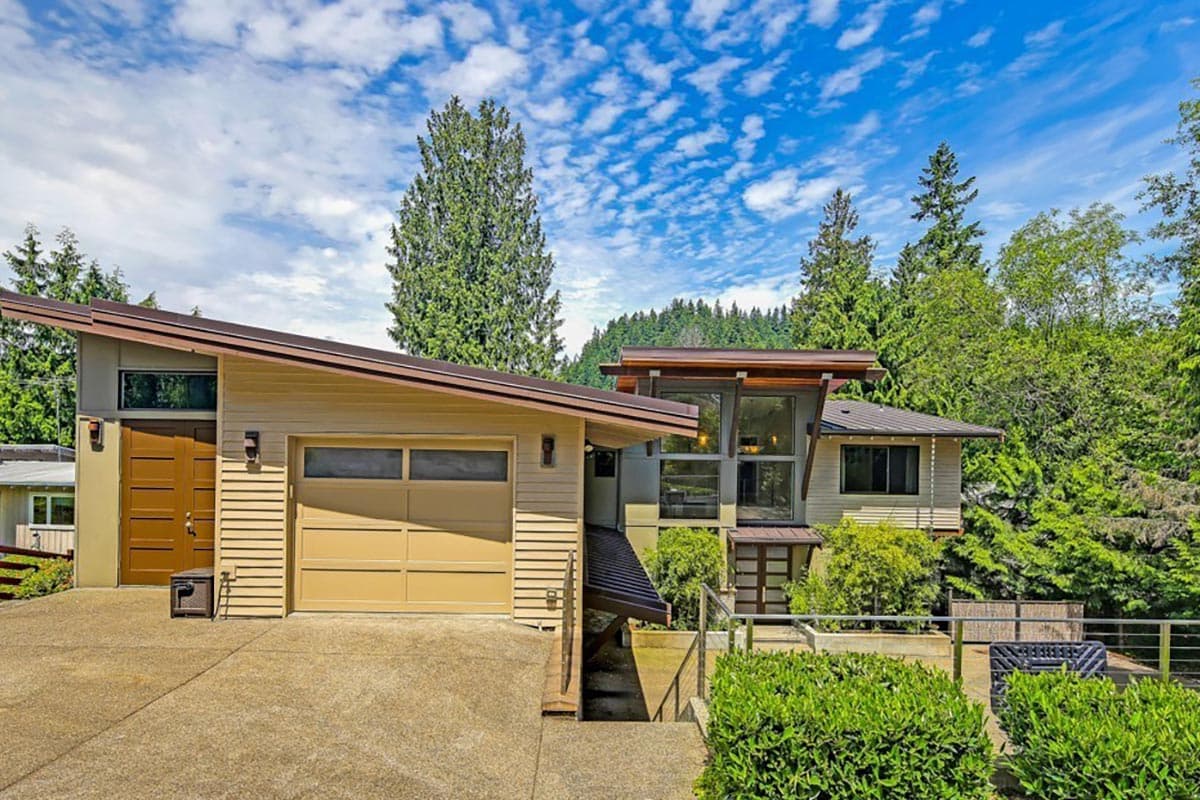 House plan exterior. Modern style with a single-story design. Features include a flat roof, cantilevered roof element, and attached garage.