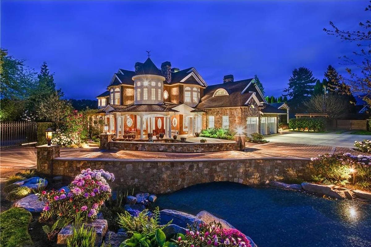 House plan exterior: Multi-story home with stone facade, wraparound porch, prominent turret, gables, and attached garage.