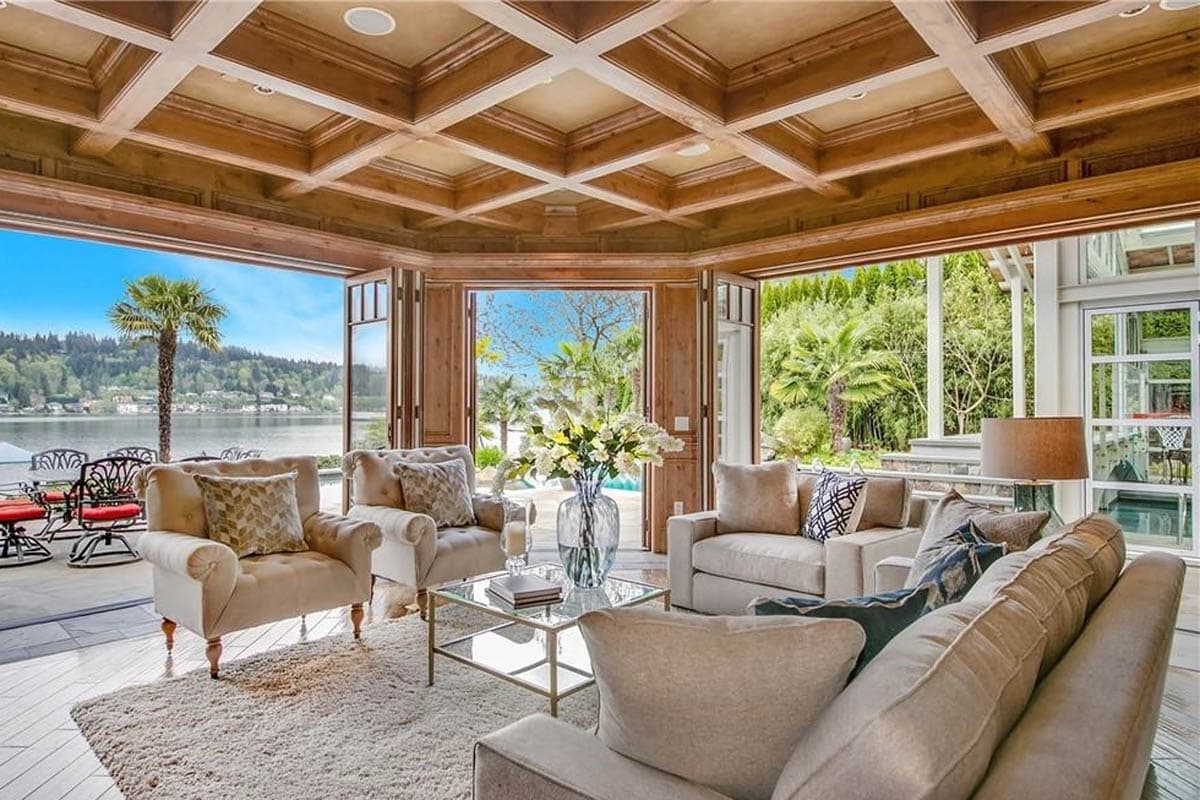 Interior living room with coffered wood ceiling, opening to a patio with lake view.