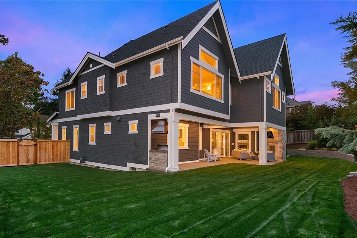 Two-story house plan exterior with a prominent gable, shingle siding, and covered outdoor living space with fireplace.