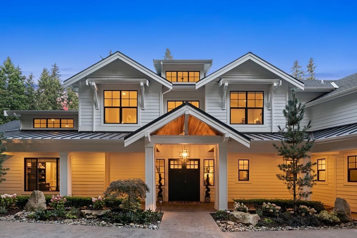 Modern Farmhouse style house plan exterior with multiple gables, dormers, white siding, and dark-trimmed windows.