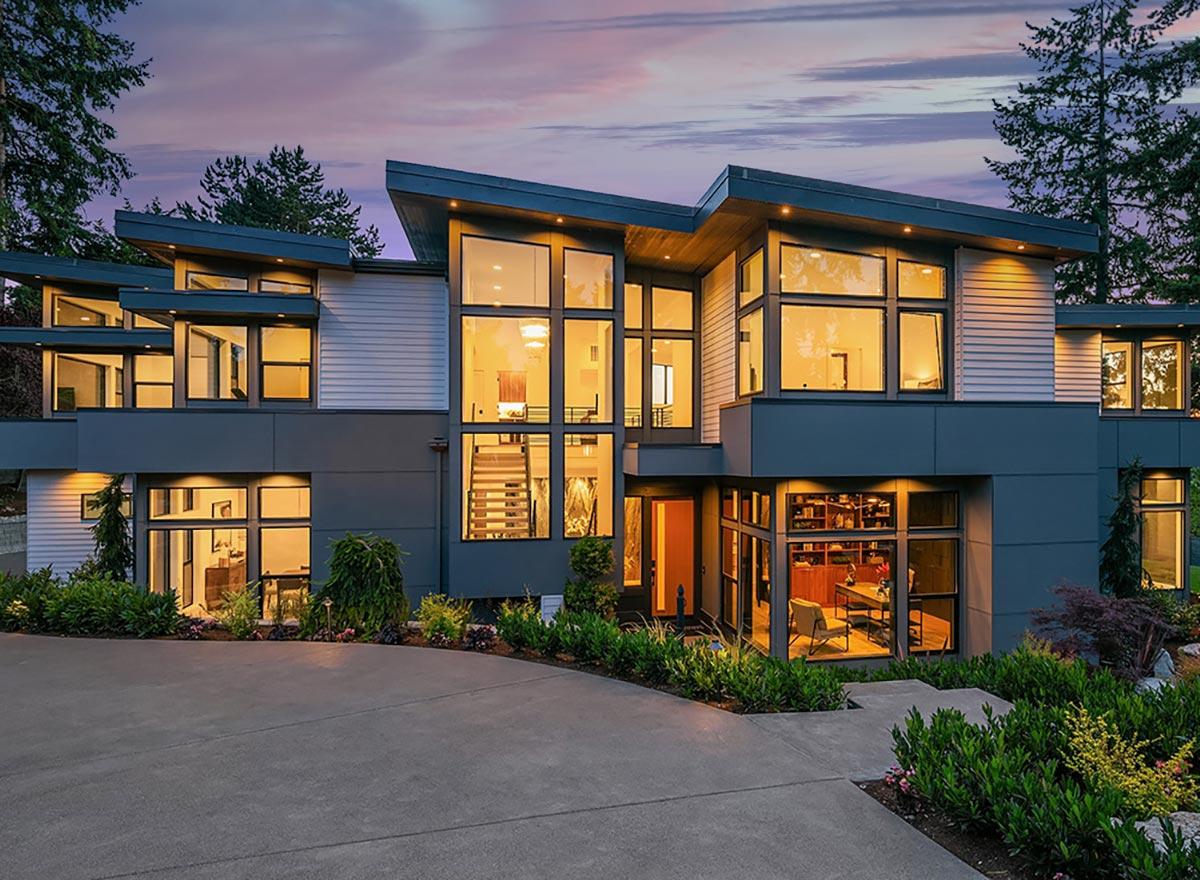 Modern house plan exterior with multiple stories, asymmetric rooflines, and extensive glass windows.
