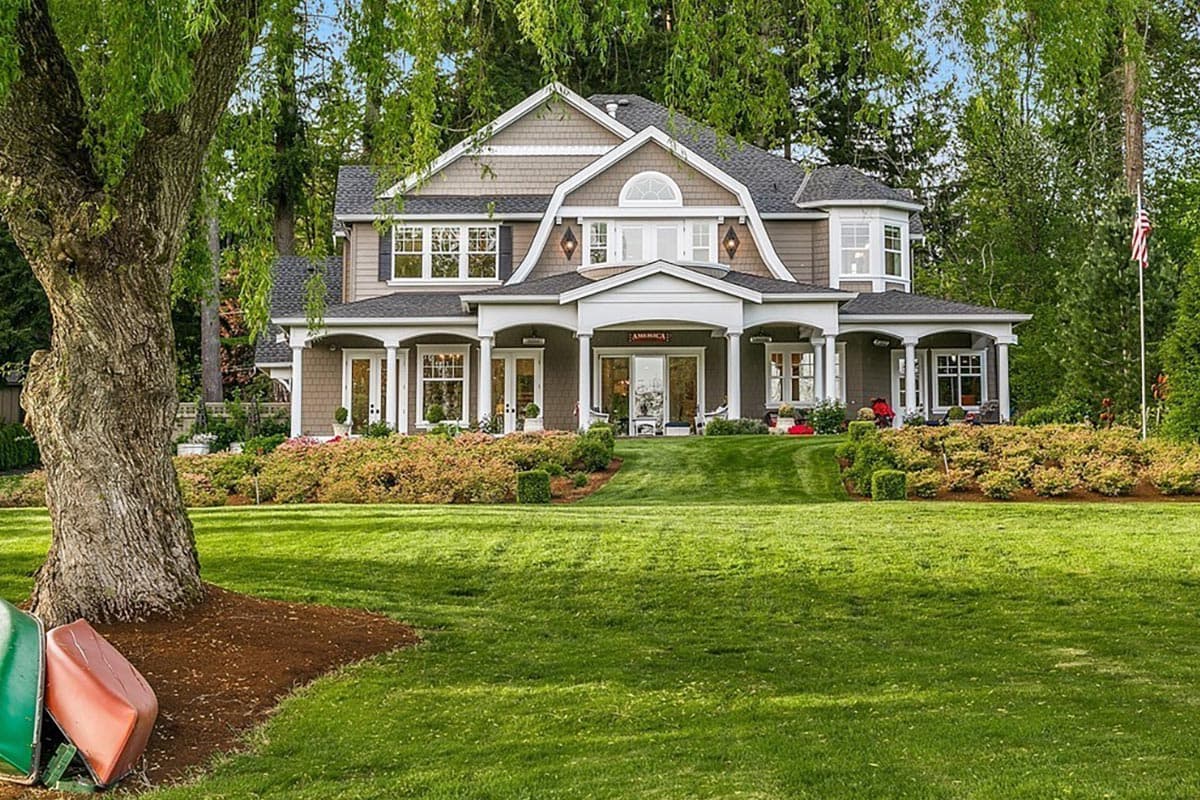 House plan exterior of a two-story home with a wraparound porch, dormers, and gabled rooflines.