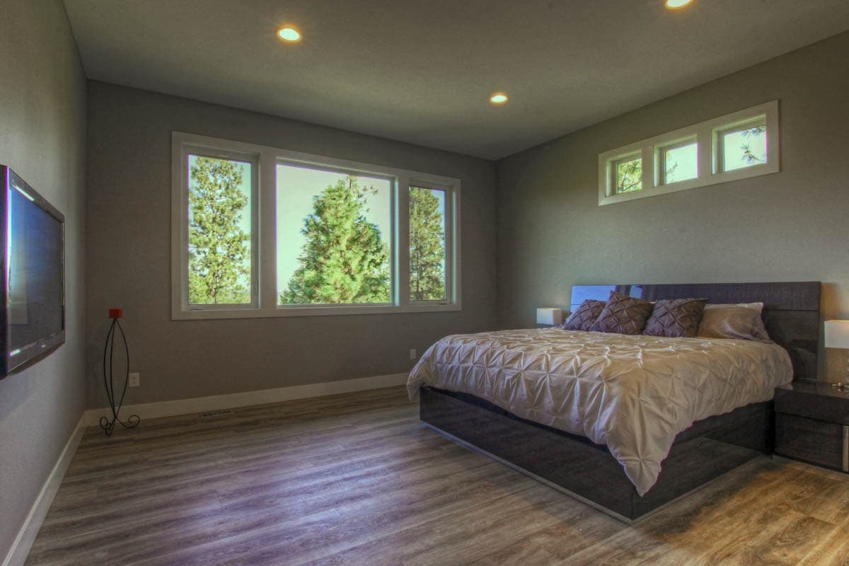 Bedroom with large picture window, horizontal windows above bed, and wall-mounted television.