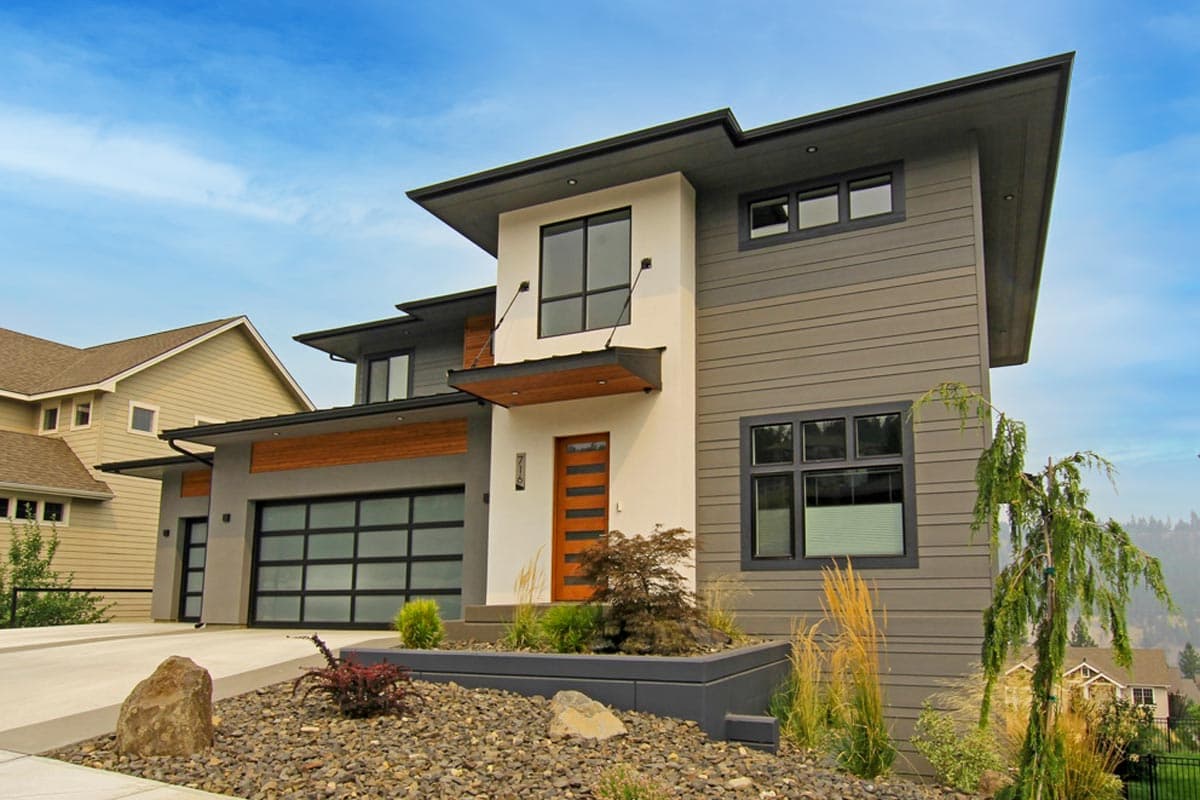 Modern two-story house plan exterior with cantilevered rooflines, horizontal siding, and a glass garage door.