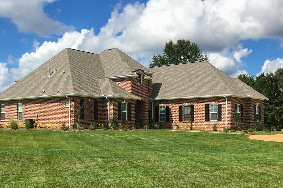 House plan exterior: One-story brick home with multiple gables, a pitched roof, and dark shutters.