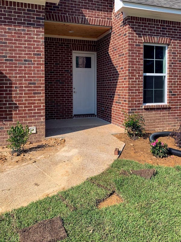 Brick house exterior with a covered entry, a glass-pane door, and a multi-pane window.