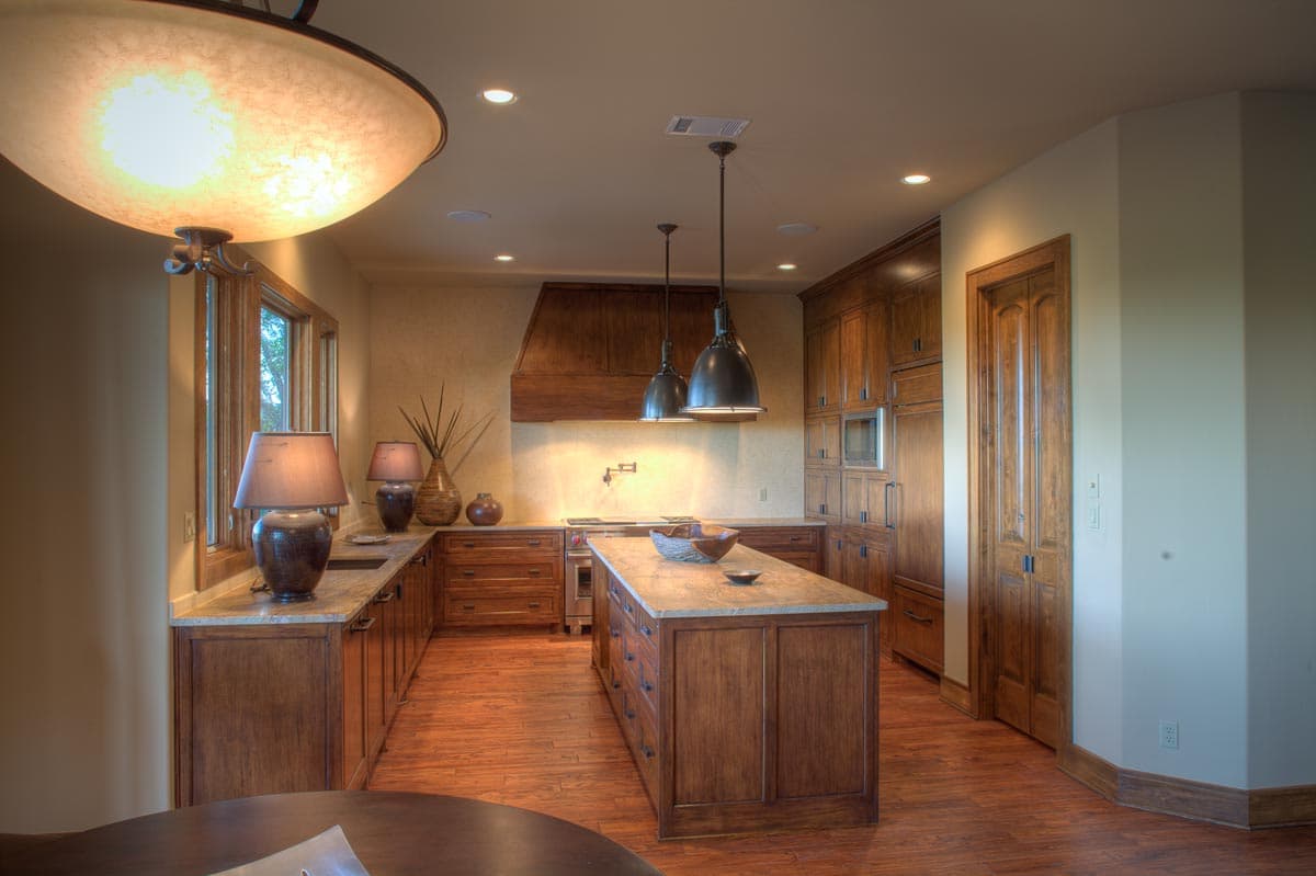 Kitchen with island, wood cabinetry, granite countertops, range hood, and pendant lighting.