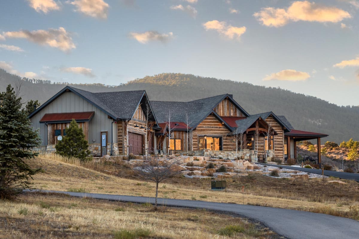 Log and timber house plan exterior with multiple gables, stone foundation, and attached garage.