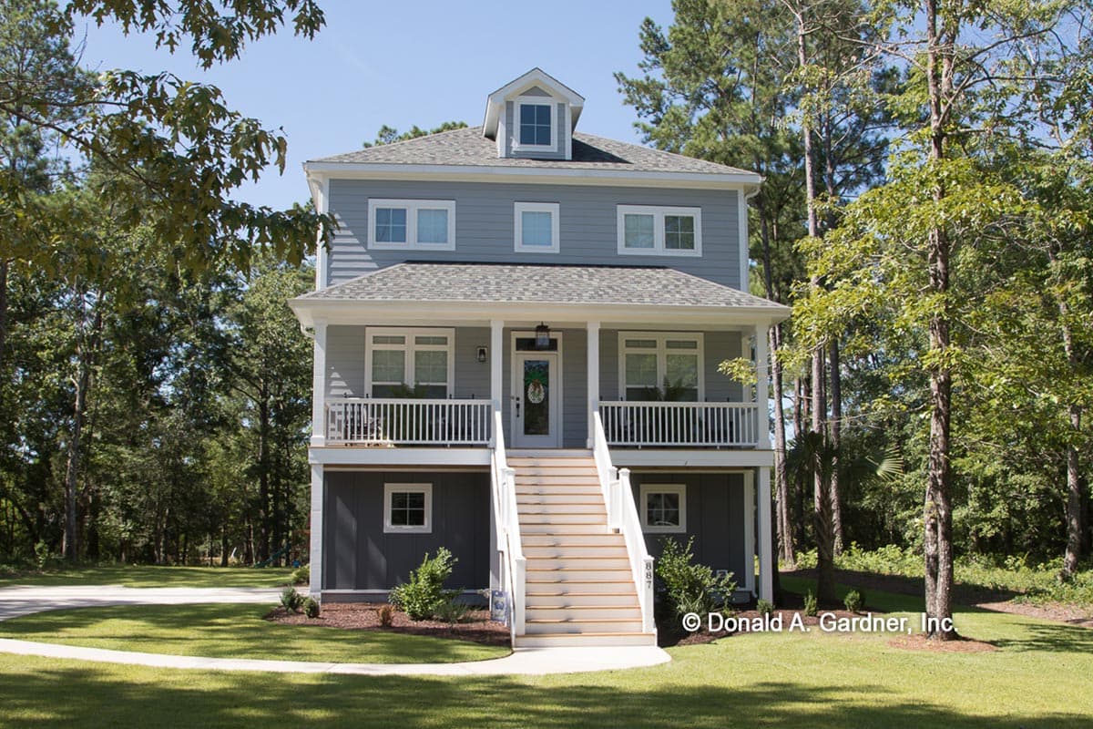 House plan exterior: Three-story home with a full front porch, dormer, and side-facing garage.