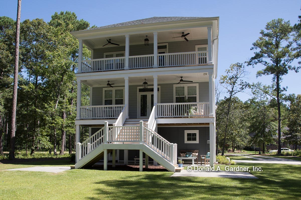 House plan exterior of a three-story home with double porches, white railings, columns, and double staircases.