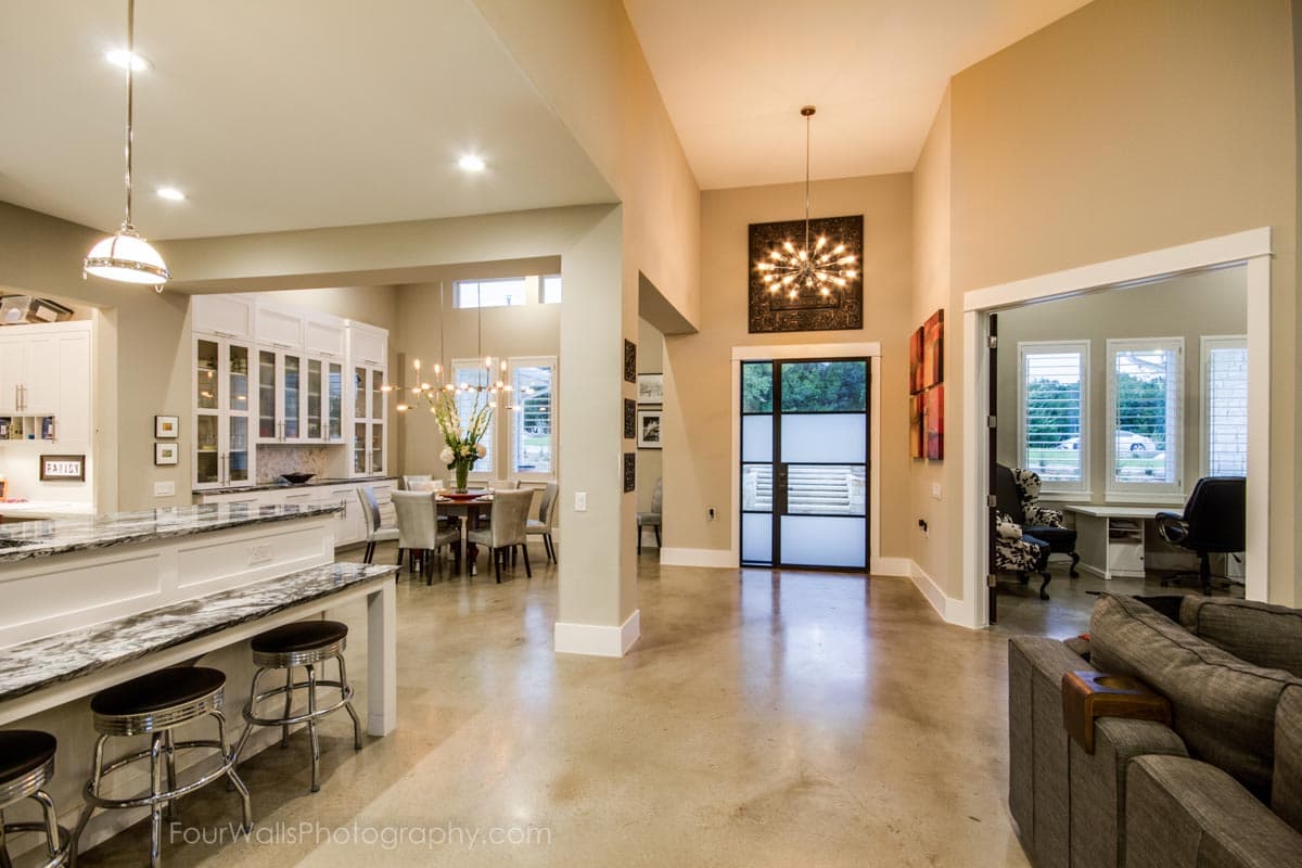 Open-concept interior with kitchen island, dining area, and great room featuring a tall ceiling and modern door.