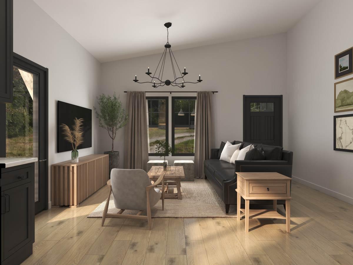 Living area with vaulted ceiling, black sofa, armchair, wood flooring, and a black chandelier.