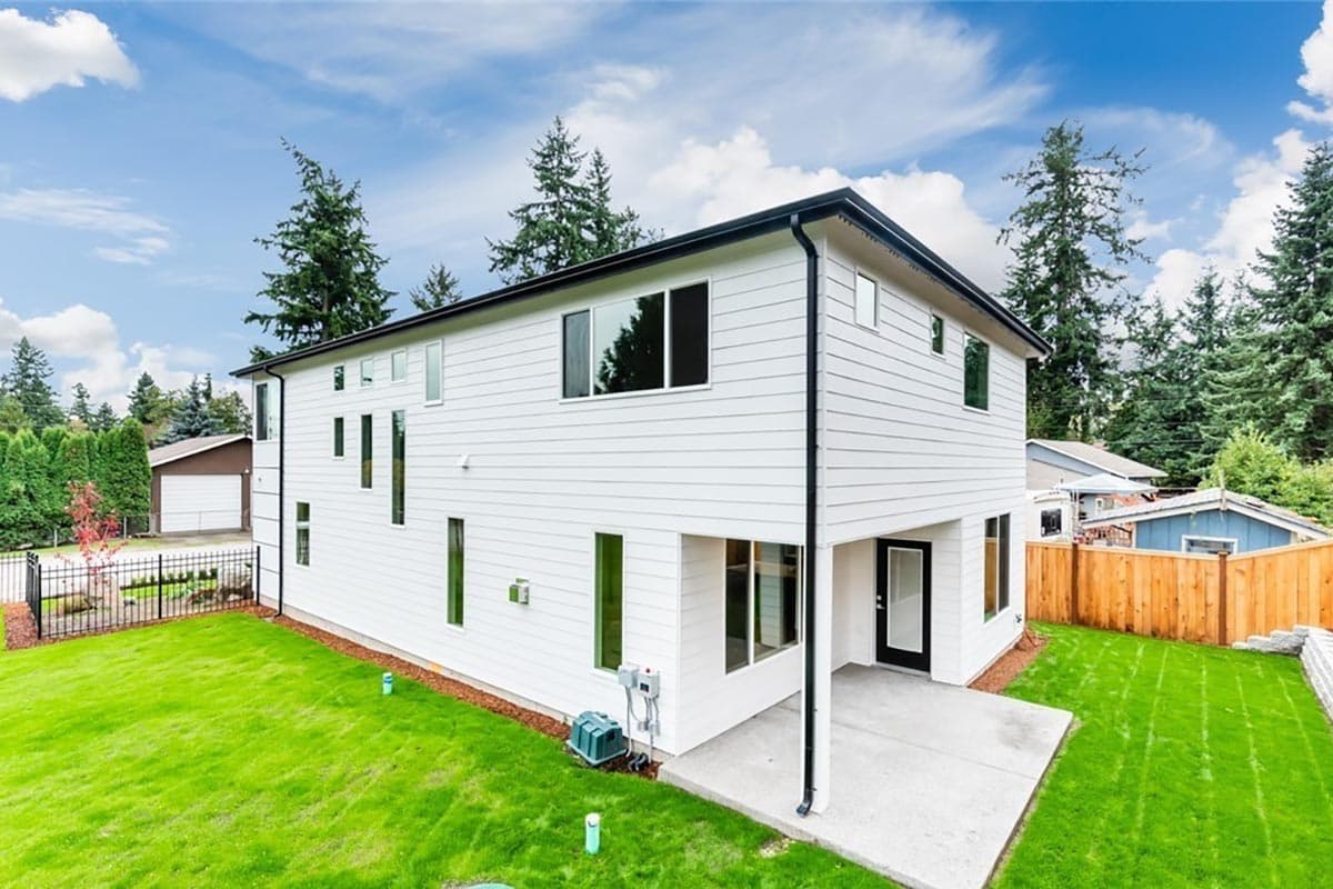 House plan exterior of a two-story modern home with horizontal siding, a covered patio, and numerous vertical windows.
