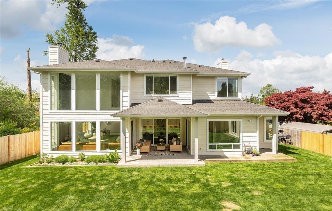Two-story house plan exterior with a covered patio, numerous large windows, and two chimneys.