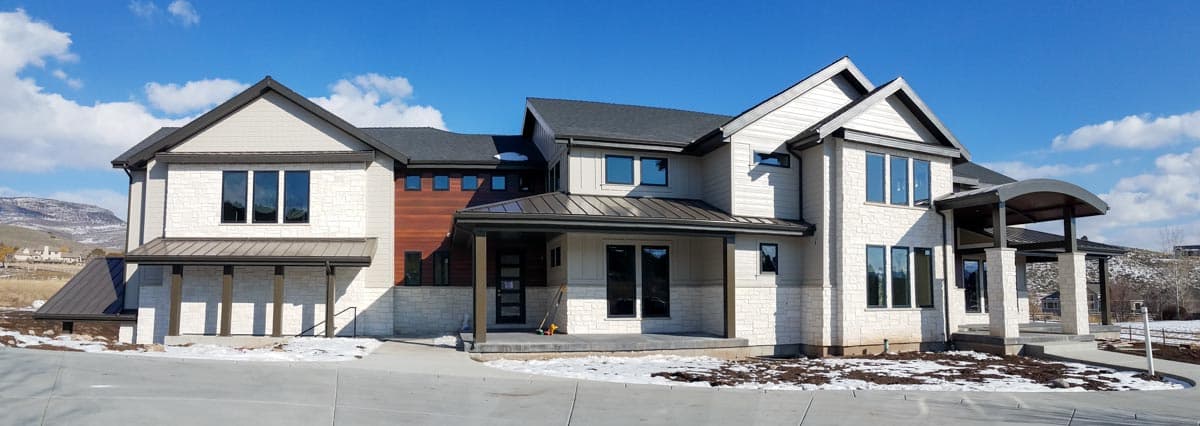 Modern house plan exterior featuring stone and siding, multiple gables, metal rooflines, and covered porches.