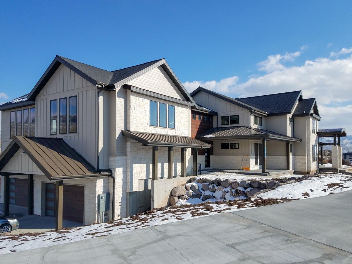 Modern house plan exterior with stone and vertical siding, multiple gables, and a triple garage.