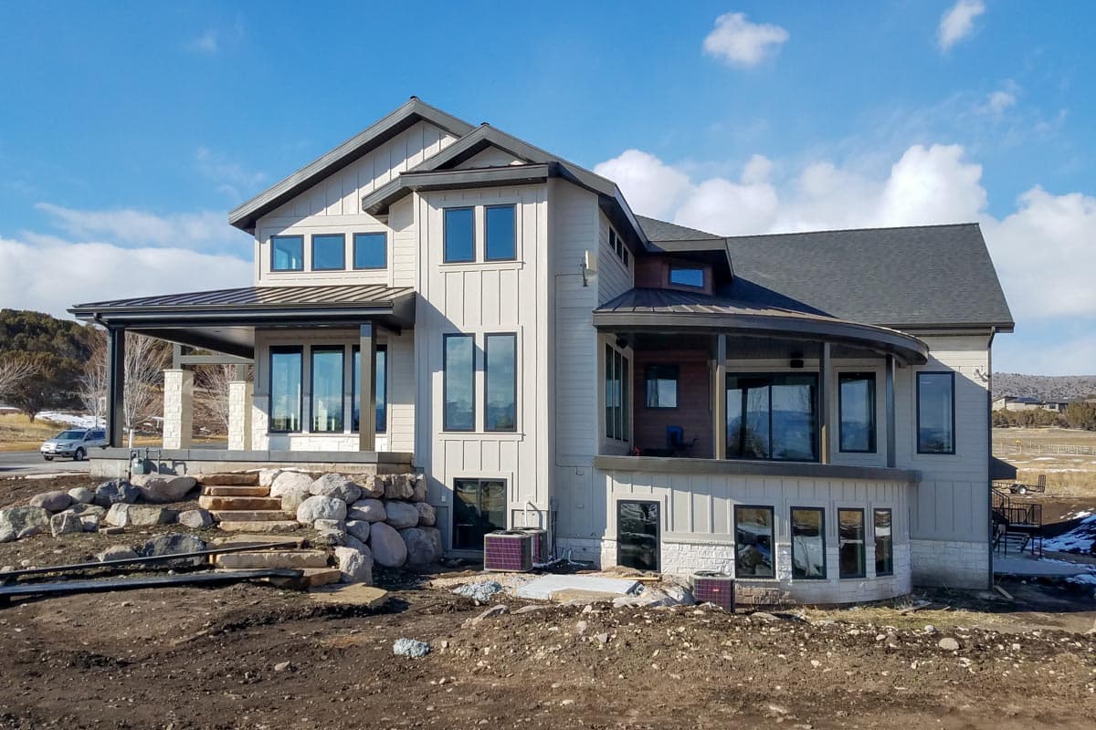 Two-story Modern Farmhouse exterior with board and batten siding, gabled roof, metal porch roof, and stone accents.