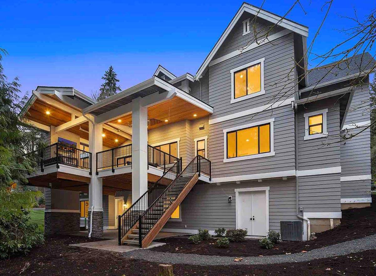 House plan exterior: Two-story modern home with multiple gabled roofs, covered decks, and a prominent exterior staircase.
