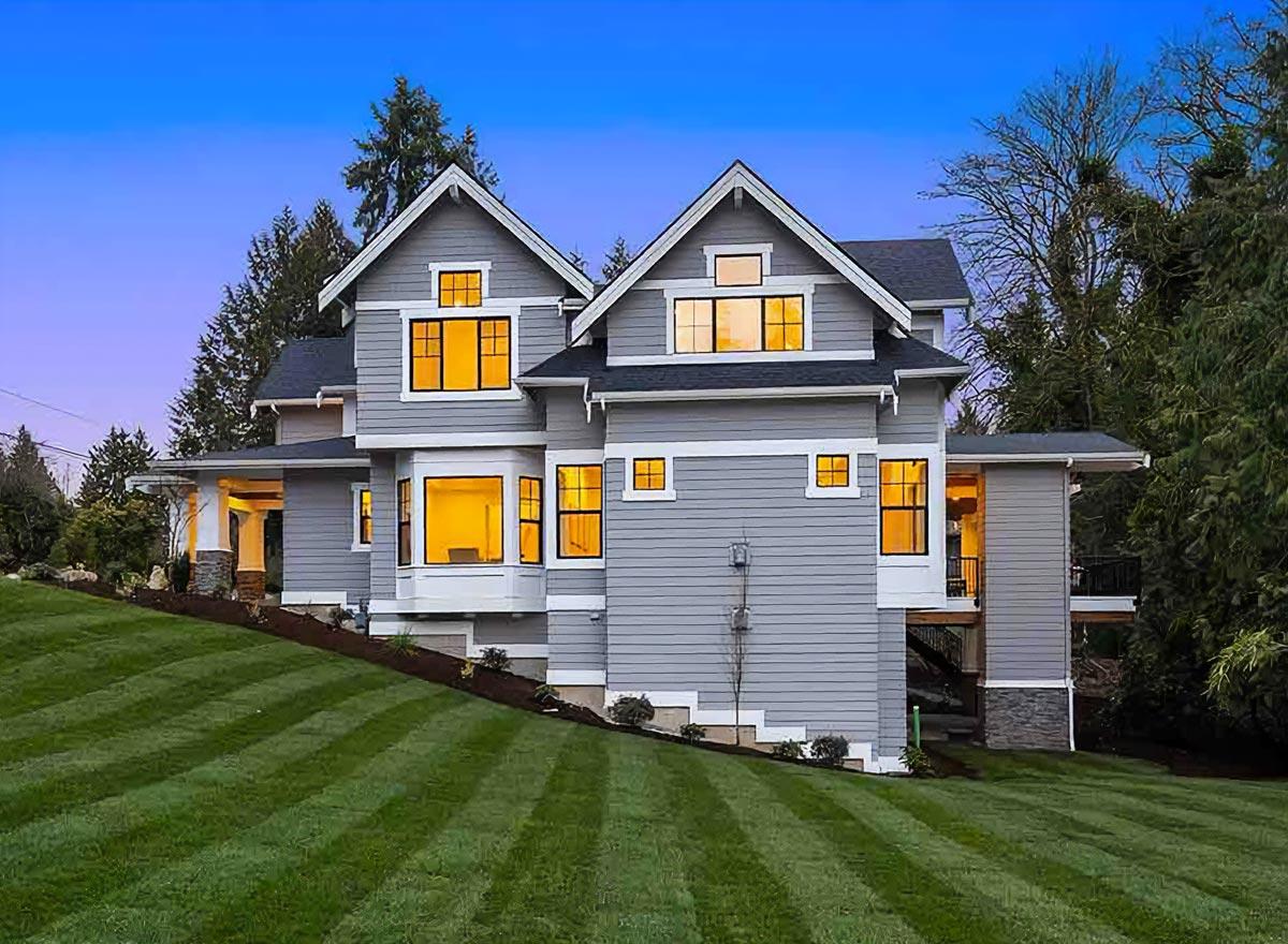 Craftsman style house plan exterior, two stories, gables, bay window, and covered porch with stone pillars.