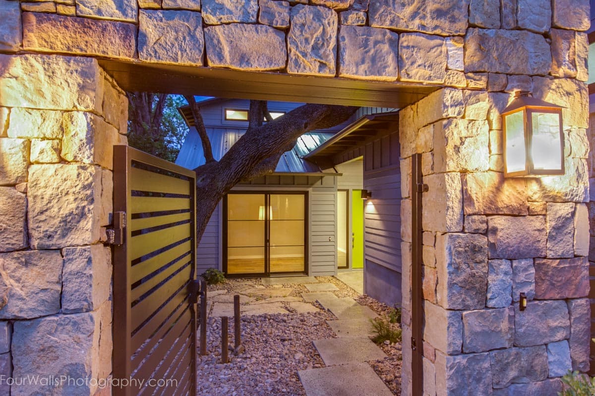 House exterior with stone gate and entrance. Modern design with metal gate and horizontal siding.