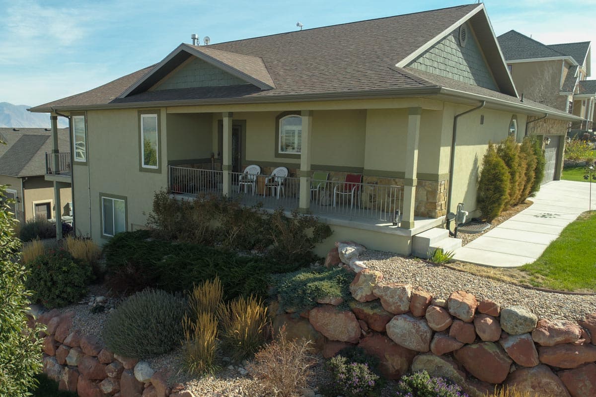 House plan exterior featuring a wraparound porch, gable rooflines, and stone accents.