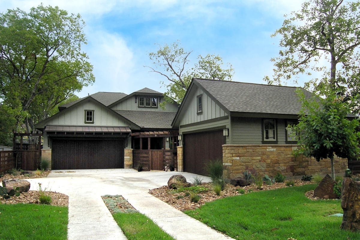 House plan exterior. Craftsman style, two stories. Features include gabled rooflines, two garage doors, and stone facade accents.