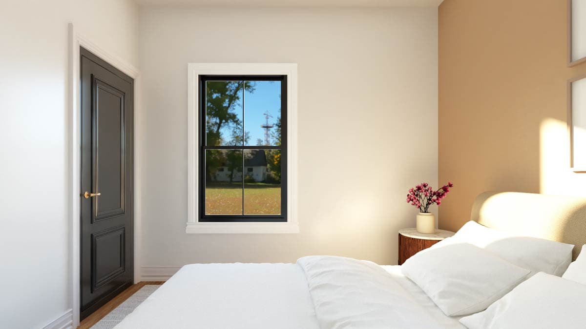 Interior view of a bedroom with a dark paneled door, a double-hung window, and a bed.