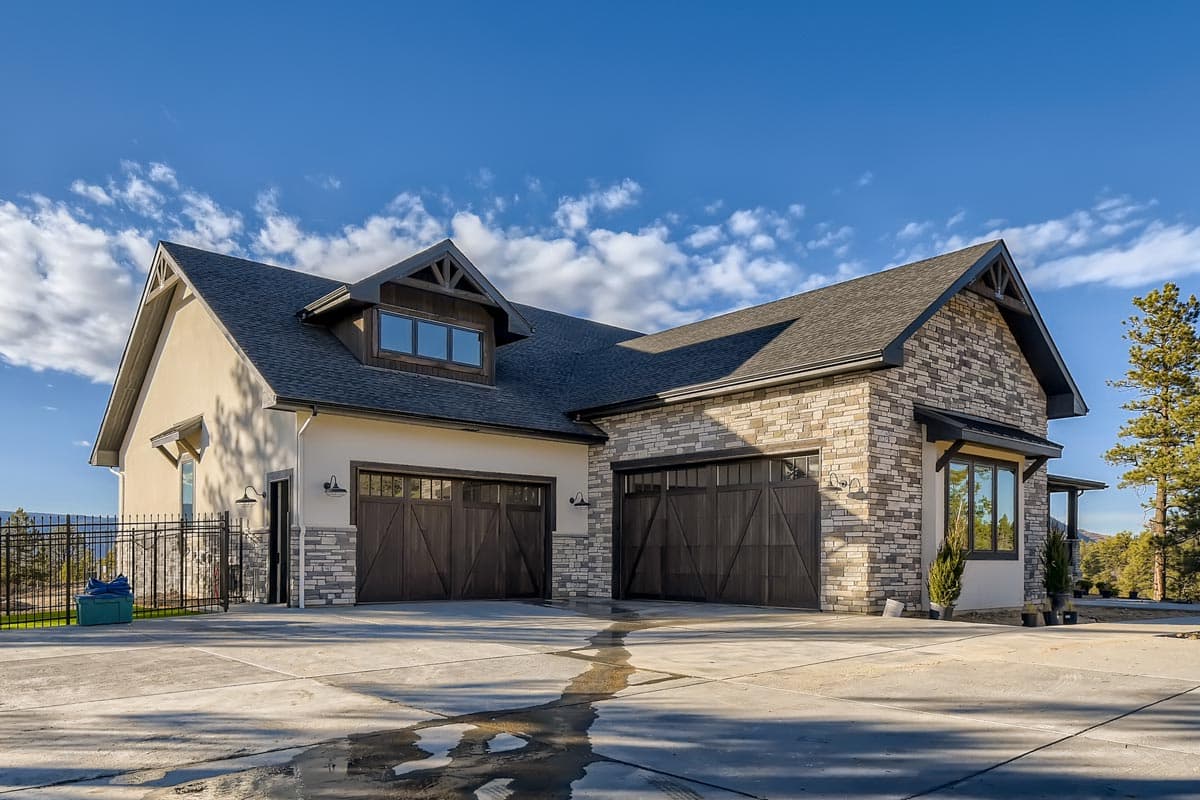 House plan exterior: Two-story Modern Farmhouse with dual garage doors, stone accents, and a dormer.