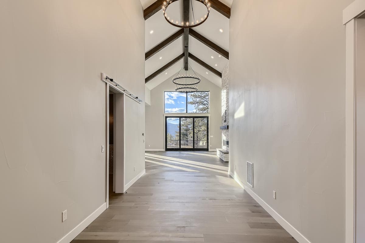 Interior view of great room with vaulted ceilings, exposed beams, stone fireplace, and large windows.
