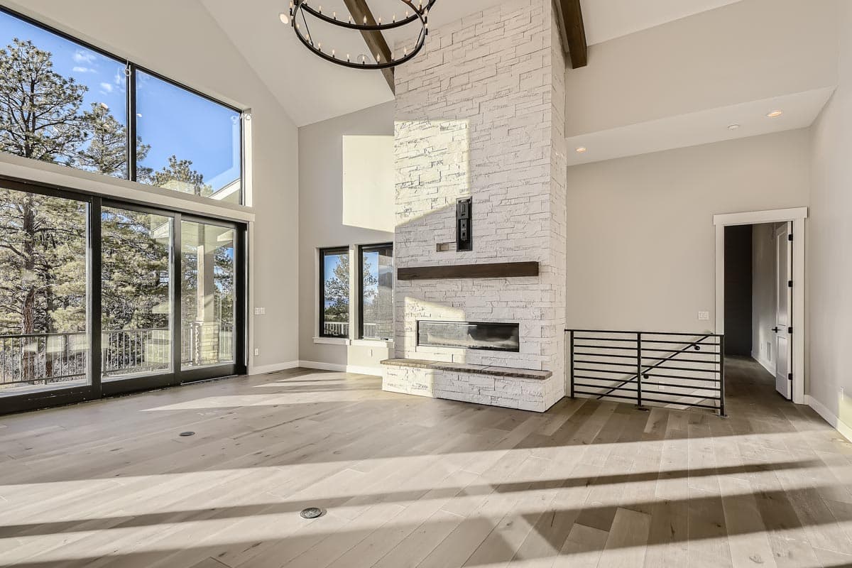 Great room with vaulted ceiling, white stone fireplace, and large windows.