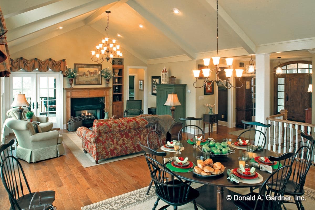 Open-concept living and dining area with vaulted ceiling, fireplace, and large windows.