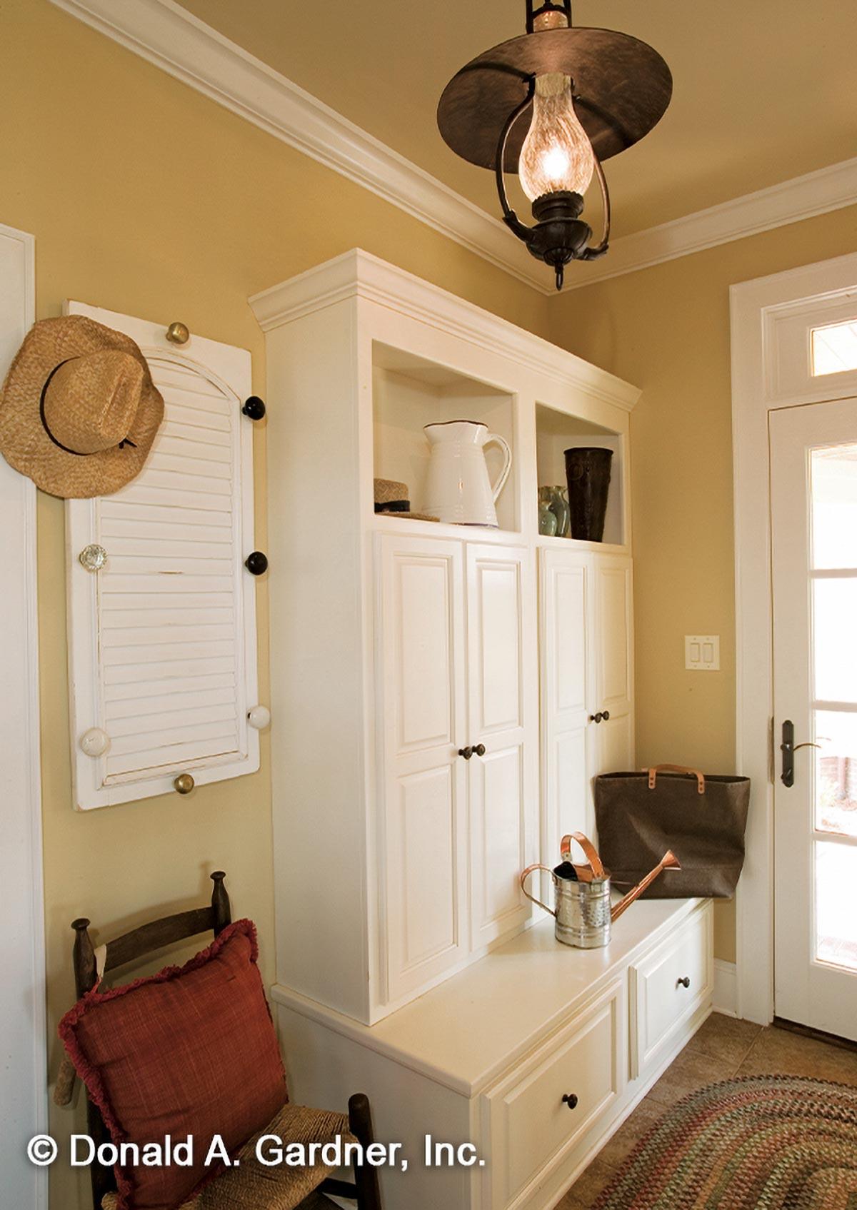 Mudroom built-in cabinetry with bench seating, louvered shutter wall decor, and a lantern pendant light.
