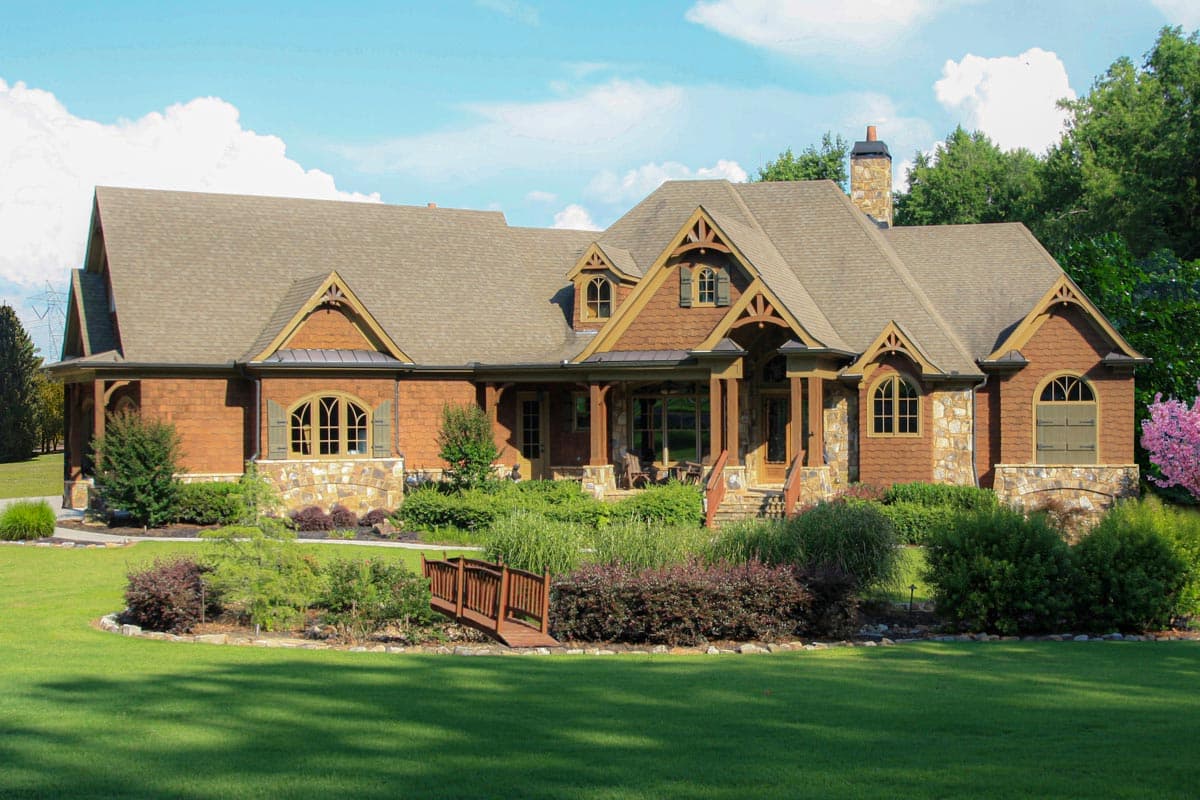House plan exterior. Craftsman style, single story. Features include a covered porch with exposed beams, gabled rooflines, and dormers.