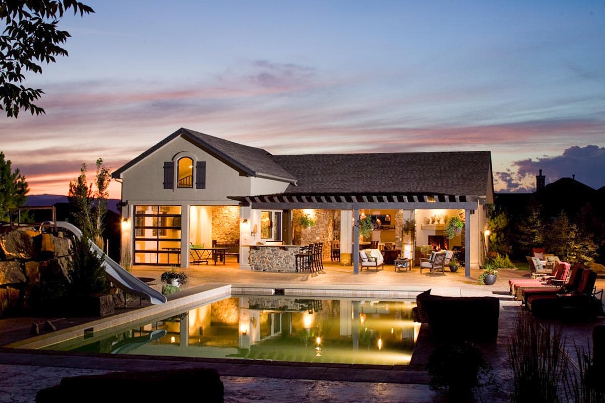 House exterior with pool and covered patio featuring outdoor bar, fireplace, and seating.