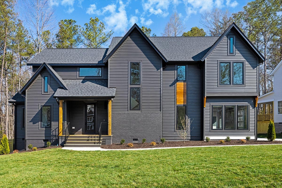 Modern house plan exterior with dark siding, gables, a covered porch with wood columns, and tall windows.