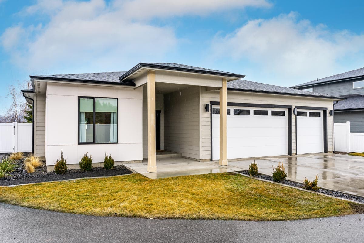 Modern single-story house plan exterior with a prominent covered entry, a large single window, and a three-car garage.
