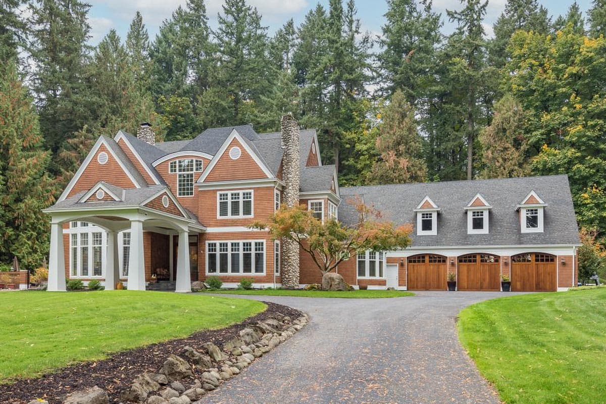 House plan exterior featuring a prominent covered entrance, stone chimney, and a three-car garage with dormer windows.